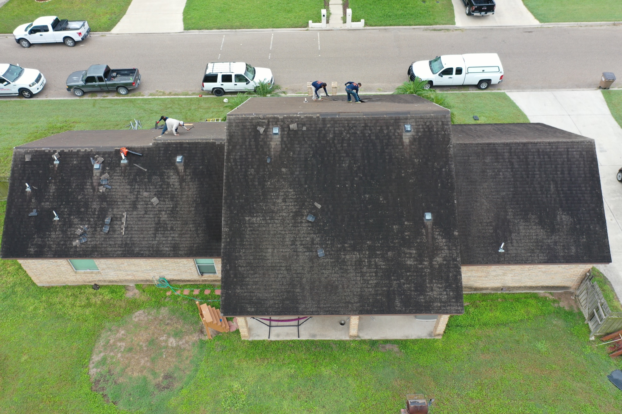 Crew removing badly weathered shingles during a full roof replacement in the Rio Grande Valley