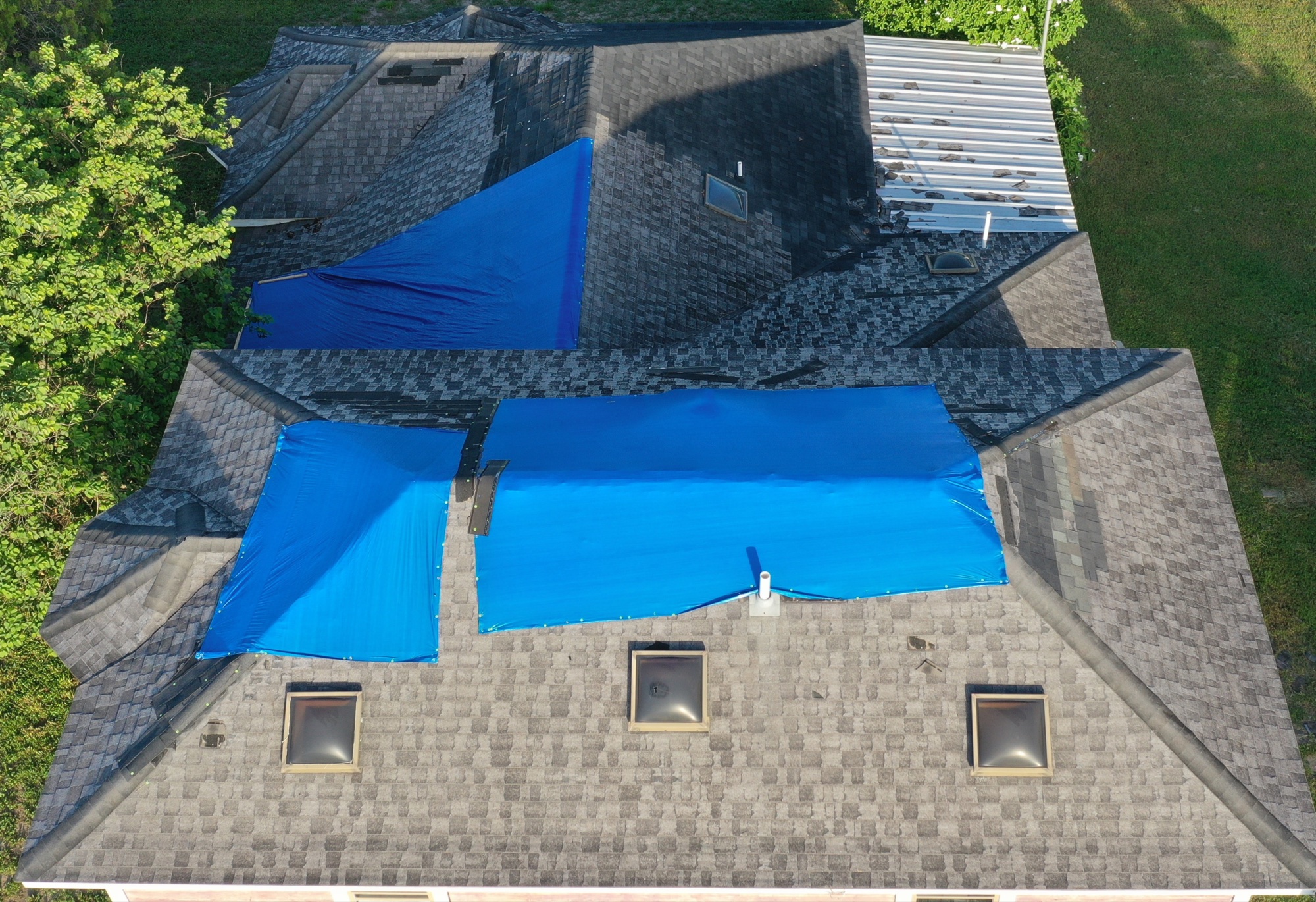Damaged shingle roof covered with emergency tarps before replacement in Mission, Texas